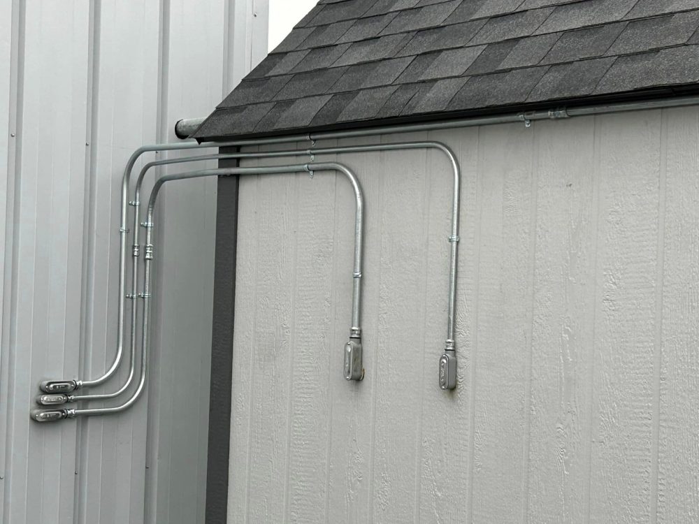Parallel EMT conduit runs with matched bends on an exterior wall