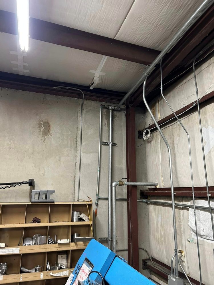 Conduit dropping down a shop wall to feed machine circuits