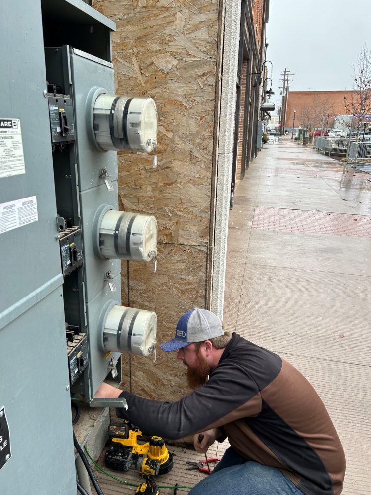 Electrician installing meter gear on a downtown Caldwell sidewalk