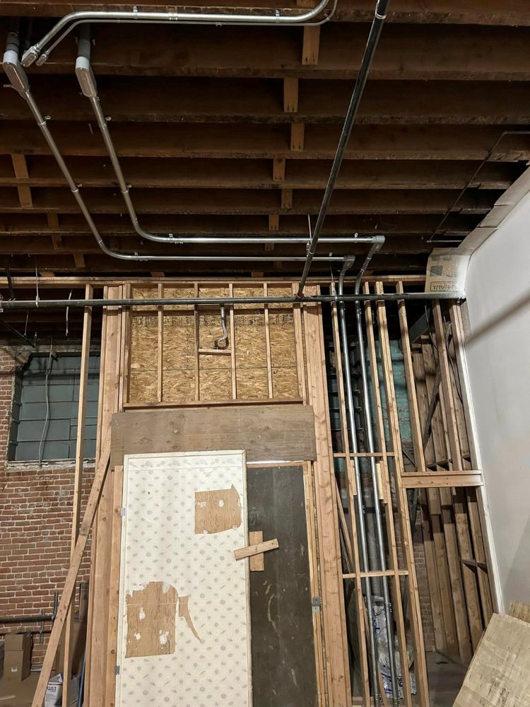 Conduit rough-in through the joists of a gutted brick building