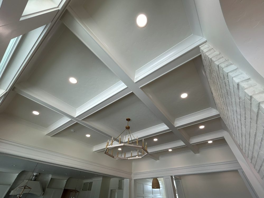 Coffered ceiling with recessed can lighting and a brass chandelier